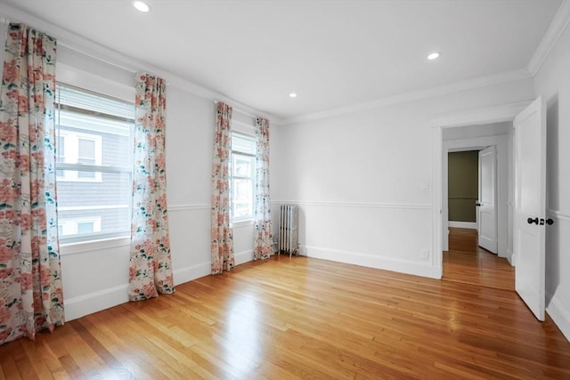 spare room with radiator heating unit, plenty of natural light, light wood-style floors, ornamental molding, and recessed lighting
