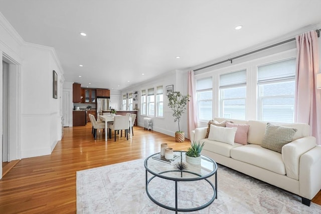living room featuring crown molding, light wood-style flooring, recessed lighting, and baseboards