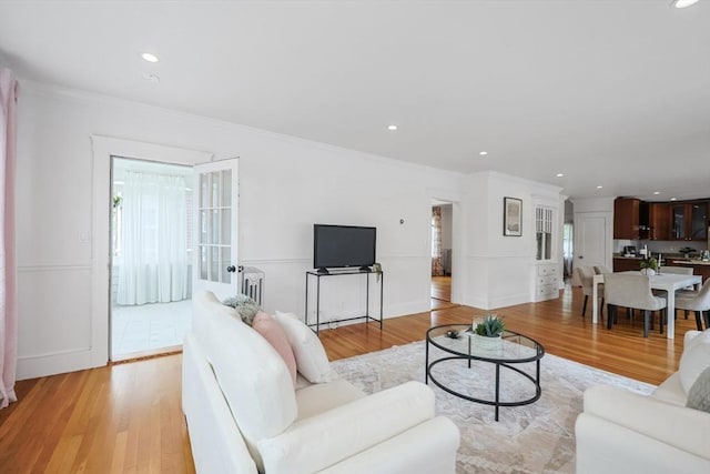 living room with light wood-style flooring, crown molding, recessed lighting, and baseboards