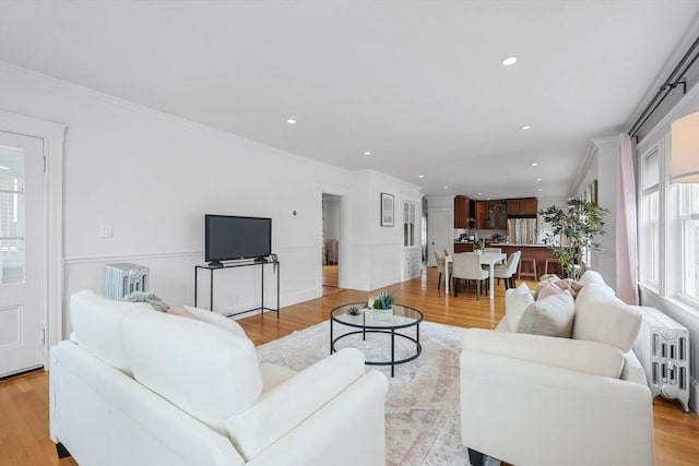 living room with ornamental molding, light wood-type flooring, recessed lighting, and radiator heating unit