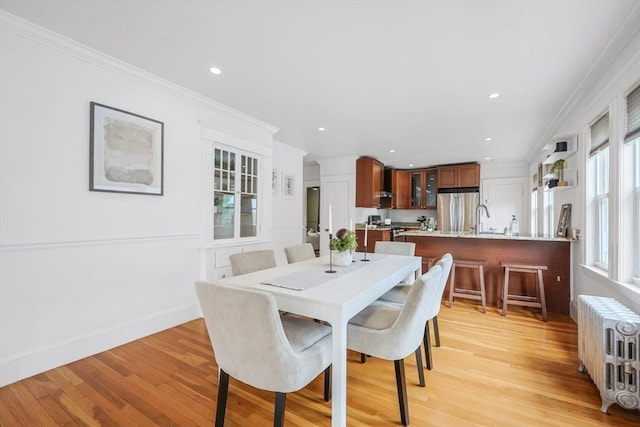 dining room with radiator, light wood finished floors, crown molding, and recessed lighting