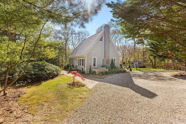 11 White Oak Trl, Barnstable, MA 02632 - view of side of home featuring a chimney, driveway, an outbuilding, roof with shingles, and a storage unit