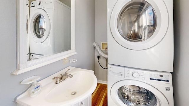 laundry room with dark hardwood / wood-style flooring, stacked washer and dryer, and sink