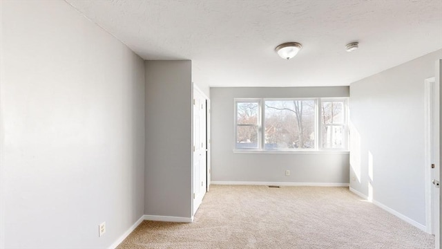 empty room with light carpet and a textured ceiling