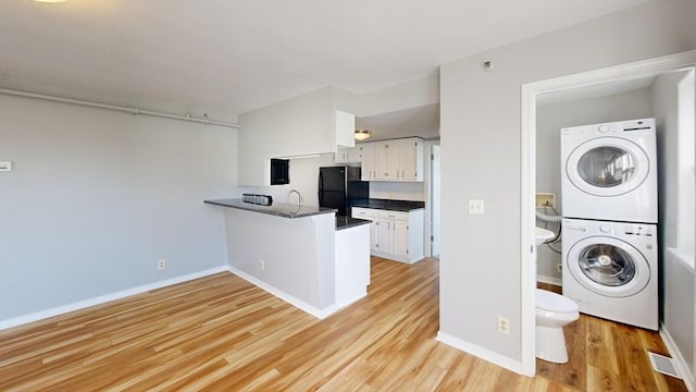 laundry room featuring stacked washer and dryer and light hardwood / wood-style flooring