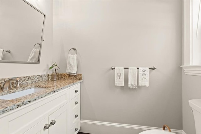 bathroom featuring baseboards, vanity, and toilet