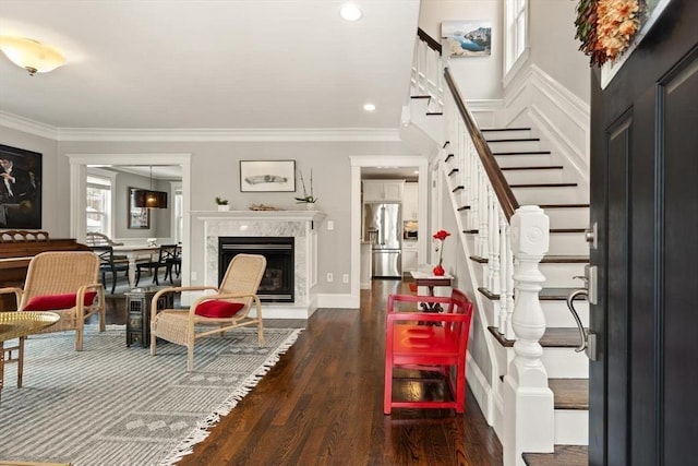 foyer featuring dark wood-style floors, recessed lighting, stairway, ornamental molding, and a high end fireplace