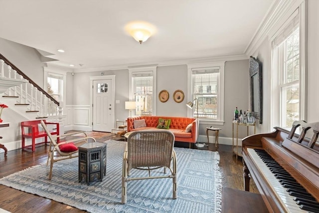 living area with dark wood-style floors, crown molding, a decorative wall, wainscoting, and stairs