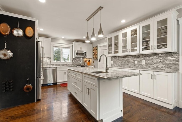 kitchen featuring appliances with stainless steel finishes, a center island with sink, glass insert cabinets, and white cabinetry