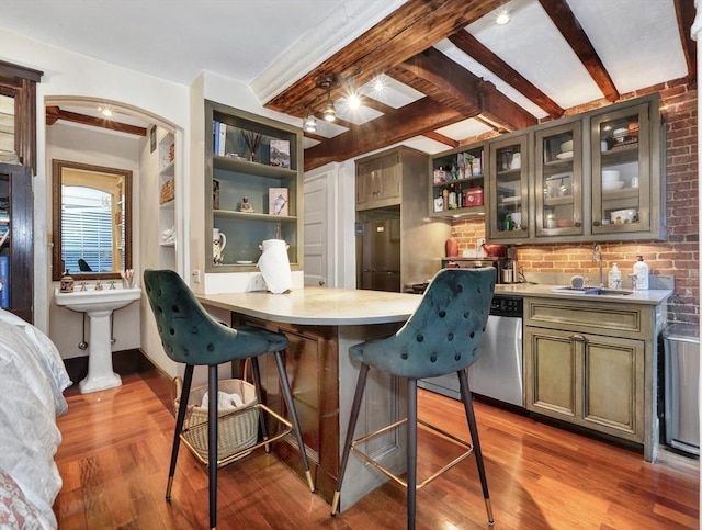 kitchen with a breakfast bar, sink, light hardwood / wood-style flooring, stainless steel dishwasher, and beam ceiling