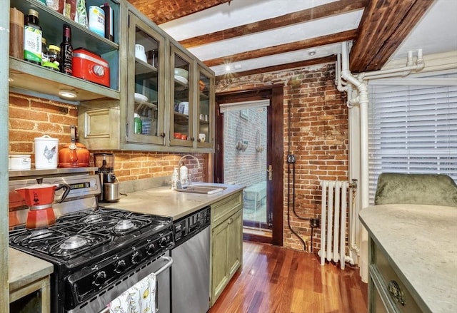 kitchen with sink, stainless steel appliances, green cabinetry, and brick wall