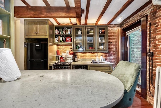 kitchen with dark hardwood / wood-style flooring, sink, black appliances, and brick wall