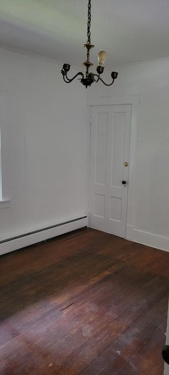 1 Barber Ave, Greenfield, MA 01301 - unfurnished dining area featuring a chandelier, dark wood-type flooring, a baseboard heating unit, baseboards, and ornamental molding