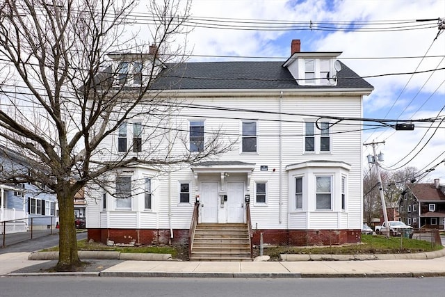 view of front of home with fence, a chimney, a shingled roof, and entry steps