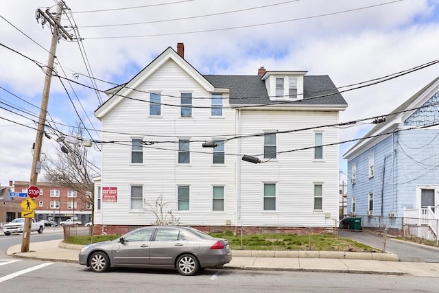 view of front of house featuring a shingled roof, a chimney, and central AC unit