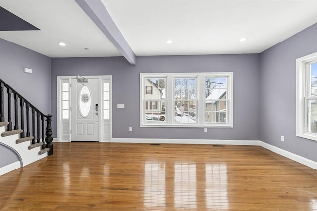 foyer entrance with wood-type flooring, beamed ceiling, and a wealth of natural light