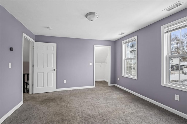 unfurnished bedroom featuring a walk in closet, carpet floors, and a closet