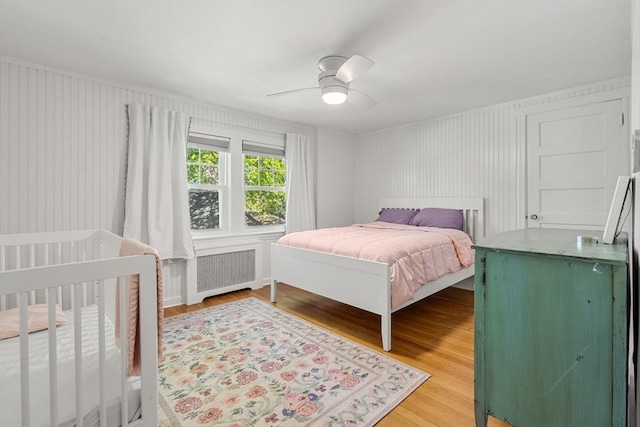 bedroom with ceiling fan, light wood-style flooring, and radiator heating unit