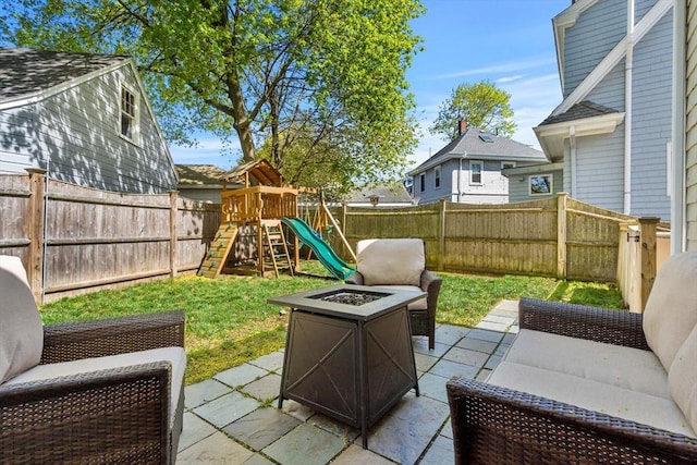 view of patio with a fire pit, a playground, and a fenced backyard