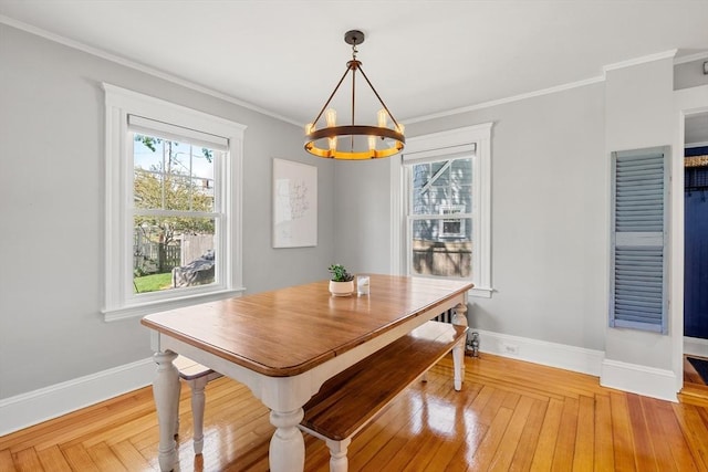 dining space with an inviting chandelier, ornamental molding, baseboards, and light wood-type flooring