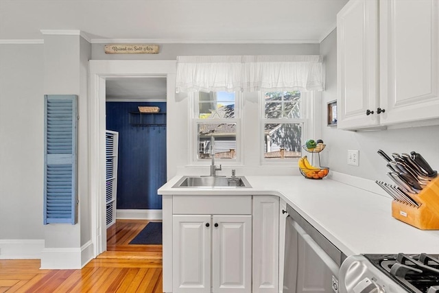 kitchen with light wood-type flooring, a sink, white cabinetry, crown molding, and appliances with stainless steel finishes