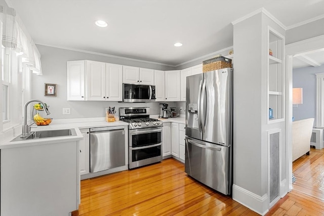 kitchen with light wood finished floors, a sink, light countertops, white cabinets, and appliances with stainless steel finishes