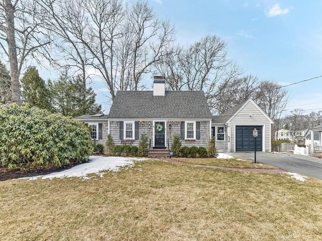 cape cod-style house featuring a chimney, a shingled roof, a garage, driveway, and a front lawn