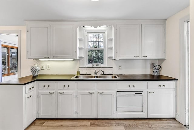 kitchen featuring dark countertops, white cabinets, open shelves, and a sink