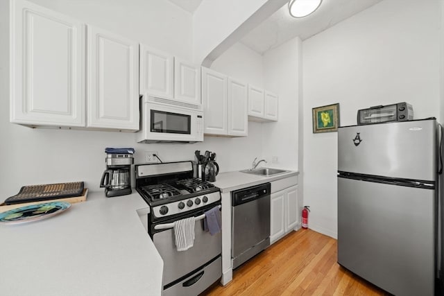 kitchen featuring white cabinets, light wood-type flooring, stainless steel appliances, and sink