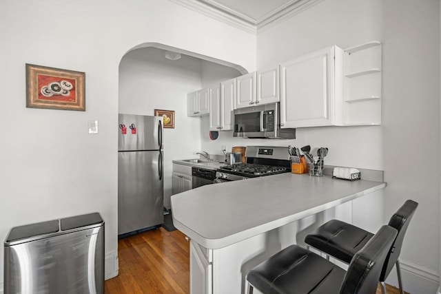 kitchen with kitchen peninsula, white cabinets, dark wood-type flooring, and appliances with stainless steel finishes