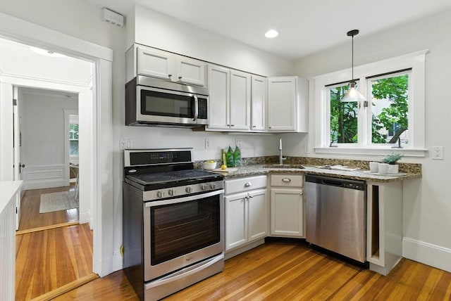 88 Brush Hill Rd, Milton, MA 02186 - kitchen with stainless steel appliances, light wood-style flooring, hanging light fixtures, white cabinetry, and recessed lighting