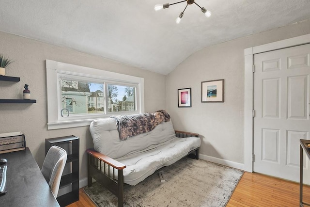 interior space featuring hardwood / wood-style floors, lofted ceiling, and a notable chandelier