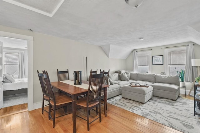 dining area with light wood-type flooring and lofted ceiling