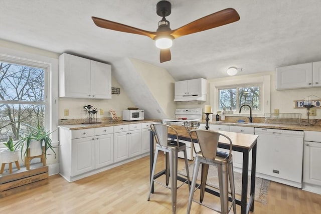 kitchen with white cabinetry, sink, ceiling fan, white appliances, and light wood-type flooring