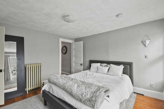 bedroom with hardwood / wood-style flooring and radiator