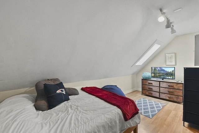 bedroom featuring vaulted ceiling with skylight and light hardwood / wood-style floors