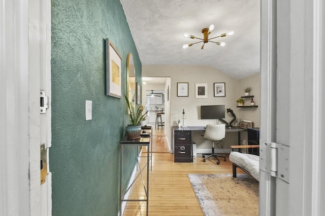 home office featuring an inviting chandelier, hardwood / wood-style flooring, and vaulted ceiling