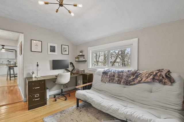 home office with light hardwood / wood-style flooring, vaulted ceiling, and a notable chandelier