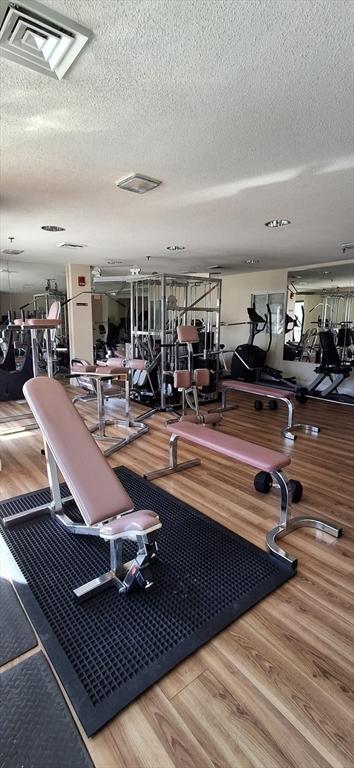 workout area featuring visible vents, a textured ceiling, and wood finished floors