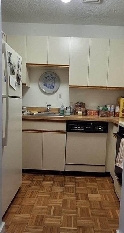 kitchen with light countertops, white cabinets, a sink, a textured ceiling, and white appliances