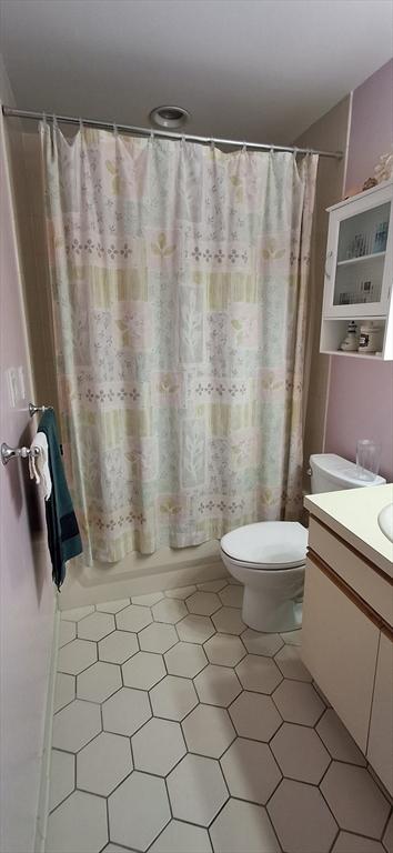 full bath with shower / tub combo, vanity, toilet, and tile patterned floors