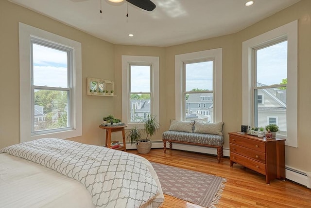 bedroom with multiple windows, light wood-style floors, a baseboard heating unit, and recessed lighting