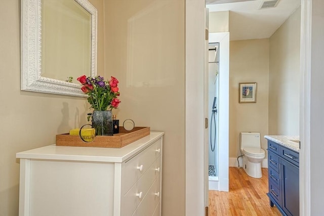 bathroom featuring wood finished floors, toilet, vanity, and baseboards