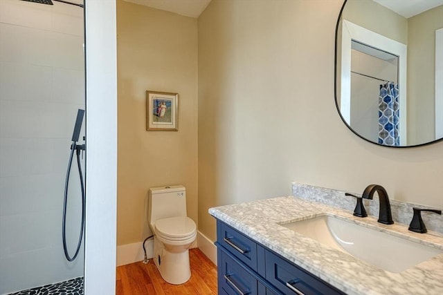 full bathroom with wood finished floors, a tile shower, vanity, and toilet