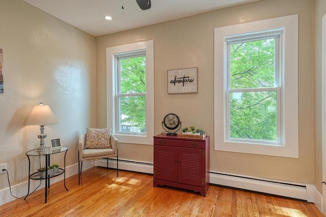 living area featuring a baseboard heating unit, light wood-type flooring, a ceiling fan, and recessed lighting