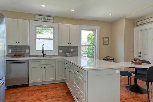 kitchen with dishwasher, a sink, a peninsula, plenty of natural light, and recessed lighting
