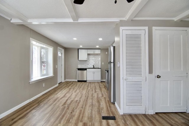 kitchen with white cabinetry, appliances with stainless steel finishes, tasteful backsplash, and light wood-type flooring