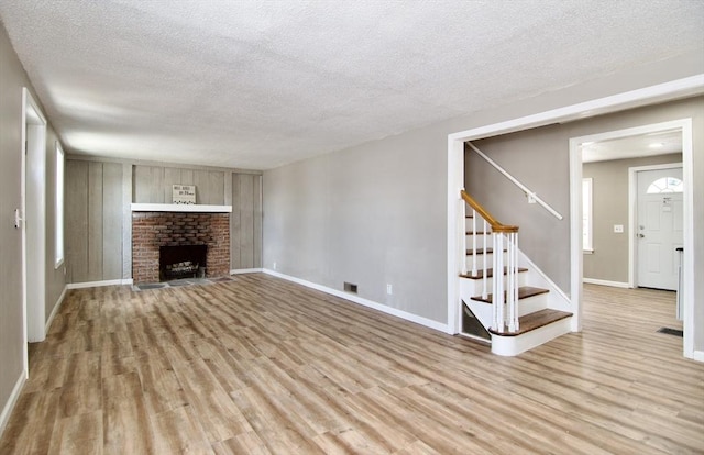 unfurnished living room with a textured ceiling, a fireplace, and light hardwood / wood-style floors