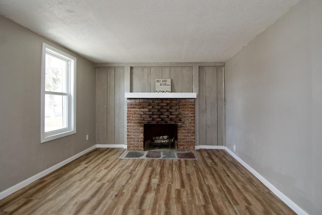 unfurnished living room with a brick fireplace, hardwood / wood-style floors, and a textured ceiling