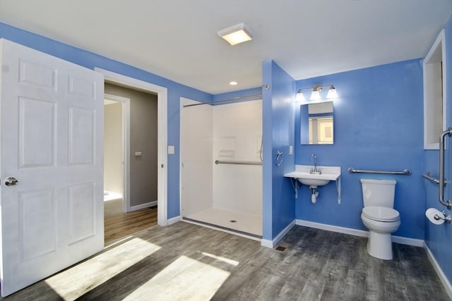 bathroom with hardwood / wood-style flooring, a shower, sink, and toilet